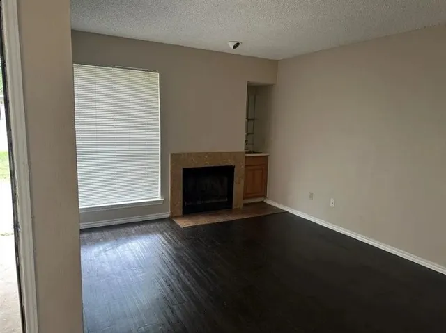 an empty room with wooden floor fire place and windows