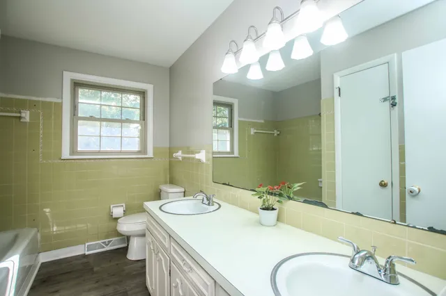 a bathroom with a double vanity sink toilet and a mirror