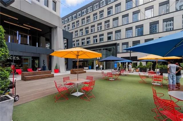a area with lots of table and chairs under an umbrella