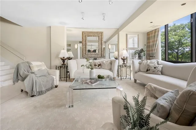 a living room with furniture white walls and a large window