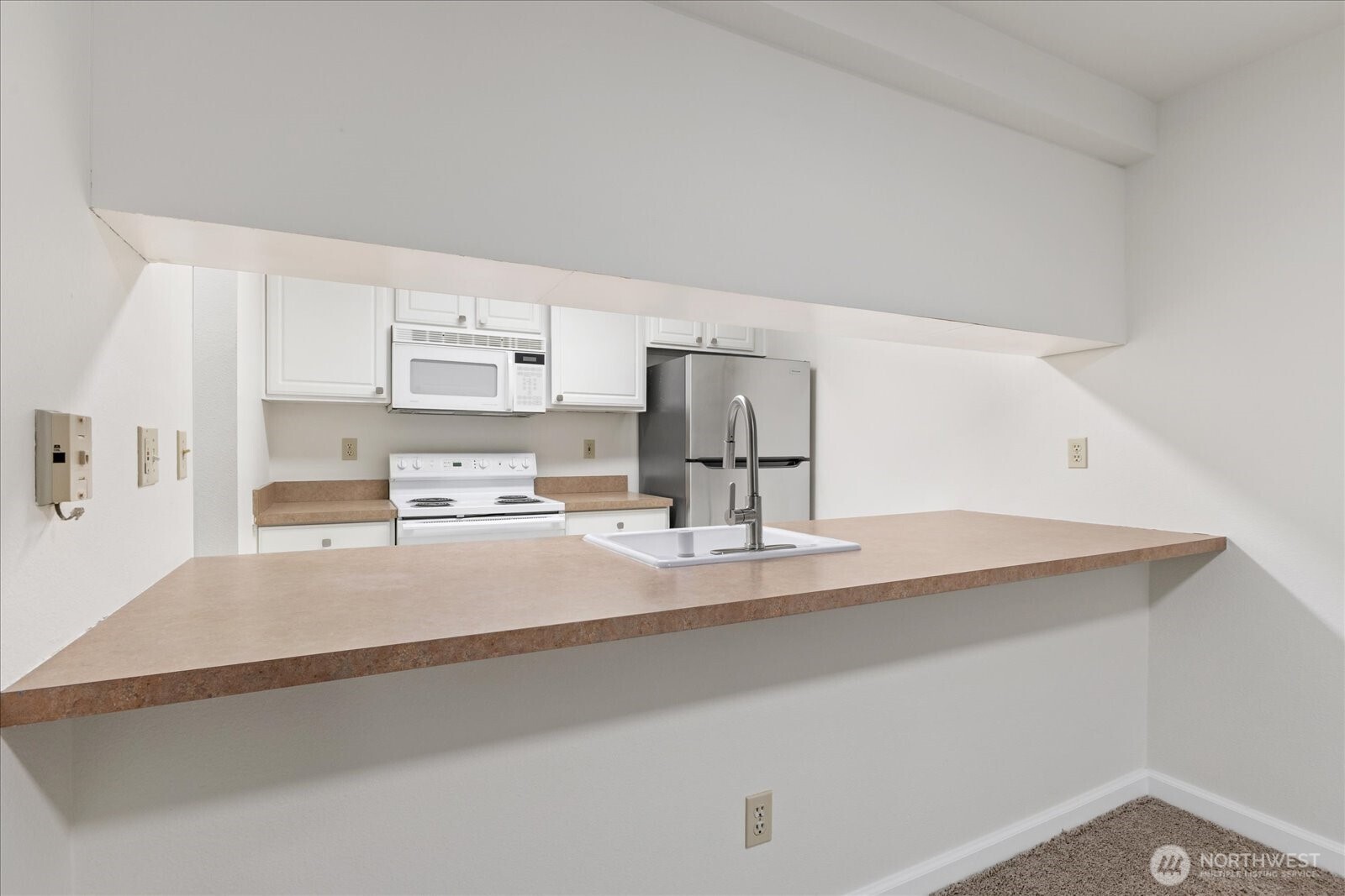 132 Northeast 95th Street, Unit B309 Seattle, WA 98115 - Photo 9 of 24 a kitchen with kitchen island a sink stove and white cabinets