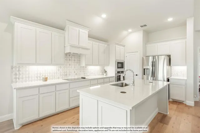 a kitchen with stainless steel appliances a sink a stove a refrigerator cabinets and a center island