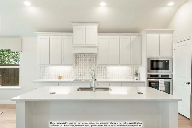 a kitchen with stainless steel appliances a sink a stove and white cabinets