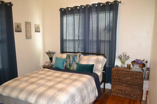 a bed sitting in a bedroom next to a window with potted plants
