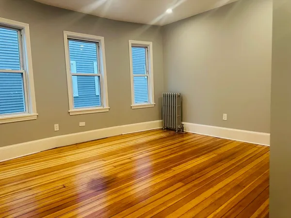 a view of an empty room with wooden floor and a window