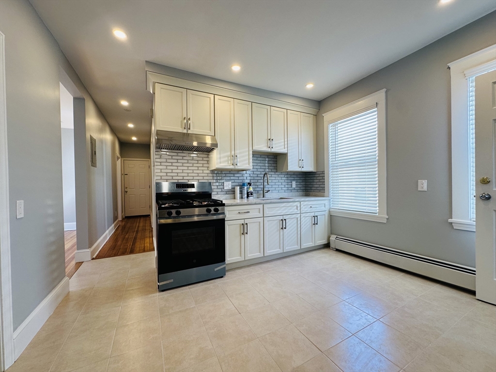 28 Melbourne Street, Unit 3 Boston, MA 02124 - Photo 7 of 27 a kitchen with stainless steel appliances kitchen island granite countertop a stove a sink and a refrigerator