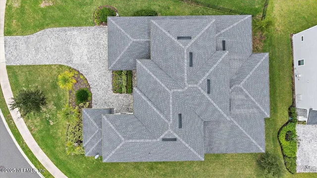an aerial view of a house with swimming pool and large trees
