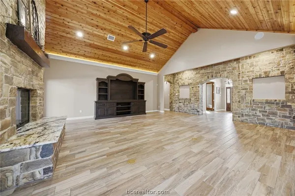 a view of an empty room with wooden floor and a kitchen