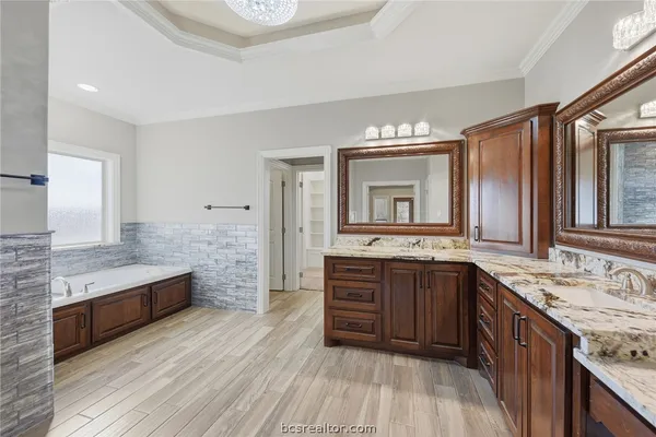 a spacious bathroom with a granite countertop double vanity sink a mirror and a bathtub