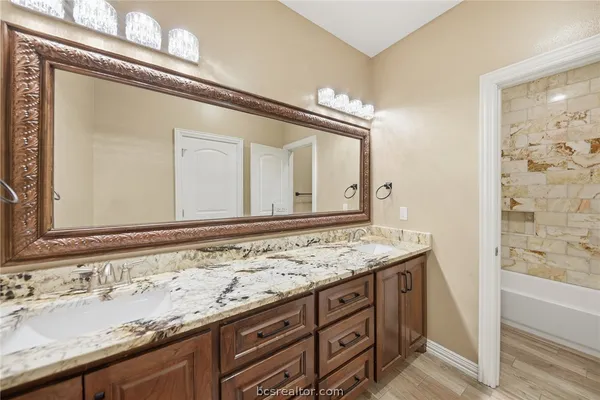 a bathroom with a granite countertop sink and a mirror