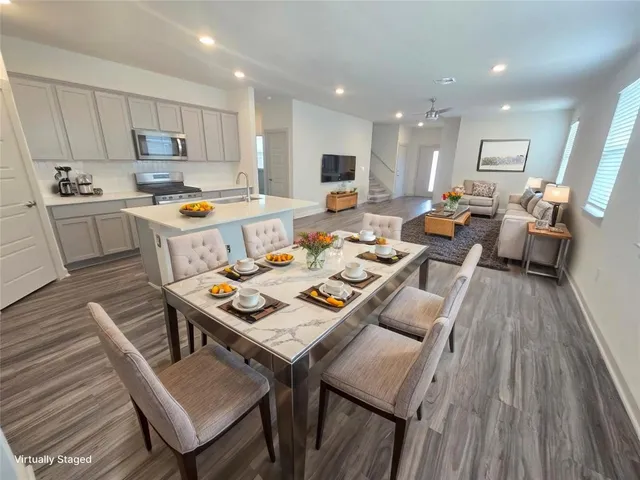 a living room with stainless steel appliances furniture a rug kitchen and a wooden floor