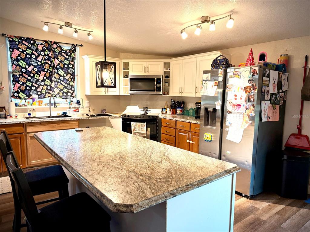 685 Eagle Watch Road Oak Hill, FL 32759 - Photo 3 of 21 a kitchen with stainless steel appliances granite countertop a sink and a refrigerator