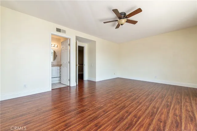 an empty room with wooden floor and a ceiling fan