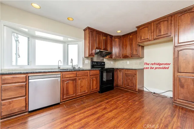 a kitchen with granite countertop wooden floors and white stainless steel appliances