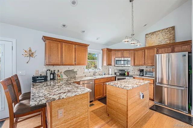 a kitchen with kitchen island granite countertop a sink stove and refrigerator