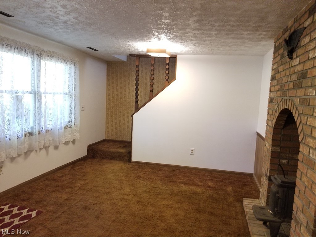 756 Cunningham Road Salem, OH 44460 - Photo 19 of 25 Unfurnished living room with a brick fireplace, brick wall, dark colored carpet, and a textured ceiling