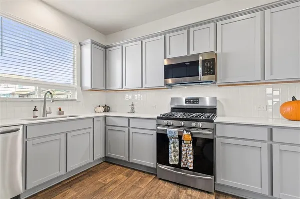 a kitchen with stainless steel appliances granite countertop white cabinets a sink and a stove