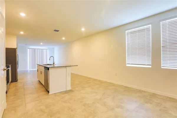 a view of kitchen with kitchen island a sink wooden floor and a refrigerator