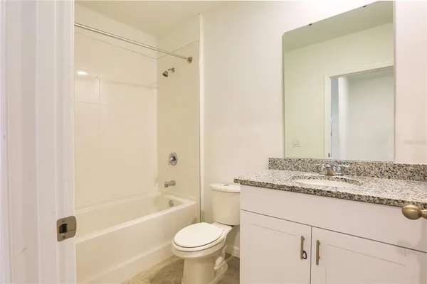 a bathroom with a granite countertop sink toilet mirror and bathtub