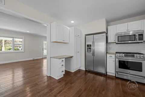 a kitchen with cabinets wooden floor and a window