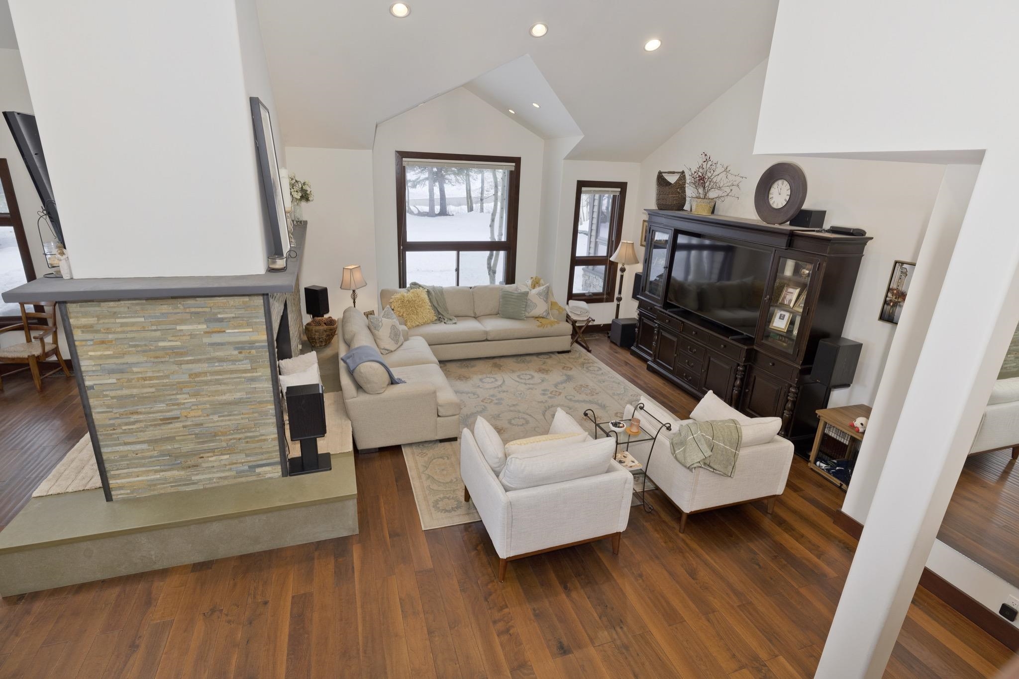 Living area featuring dark wood-style flooring, recessed lighting, and high vaulted ceiling