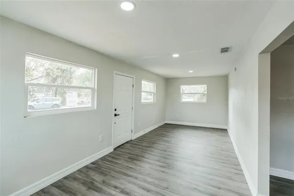 a view of an empty room with wooden floor and a window