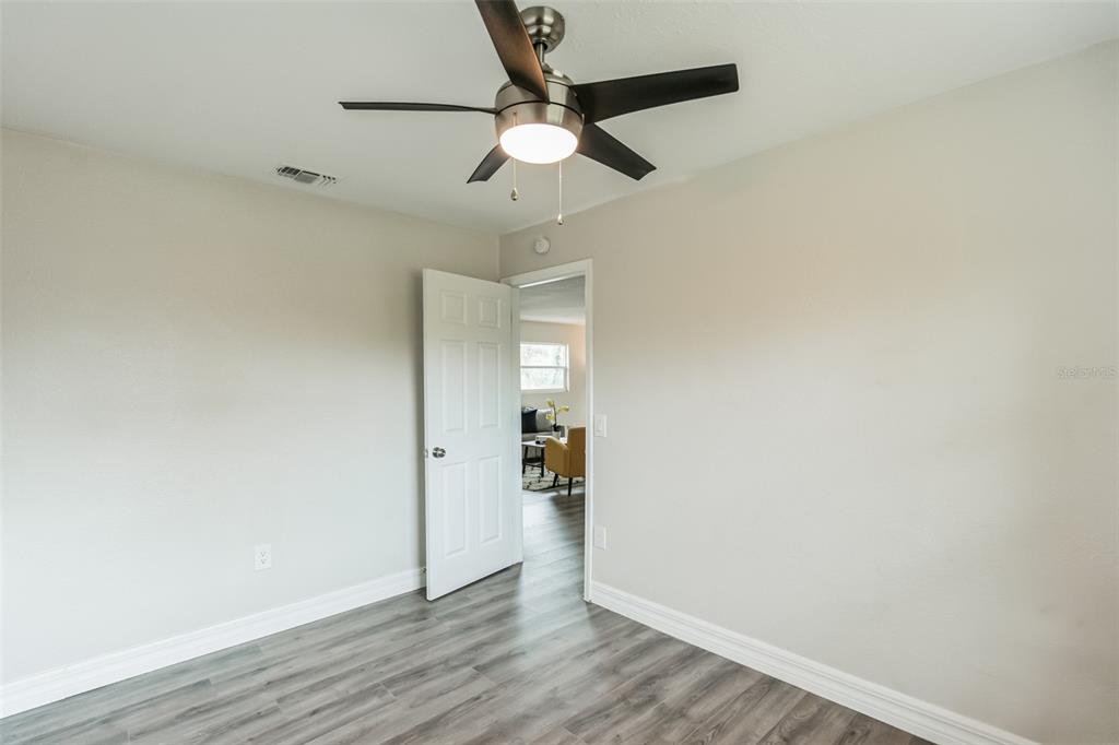 224 Singleton Avenue Arcadia, FL 34266 - Photo 19 of 24 an empty room with wooden floor chandelier fan and windows