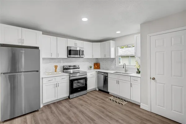 a kitchen with cabinets stainless steel appliances and a wooden floor