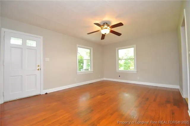 a view of empty room with wooden floor and fan