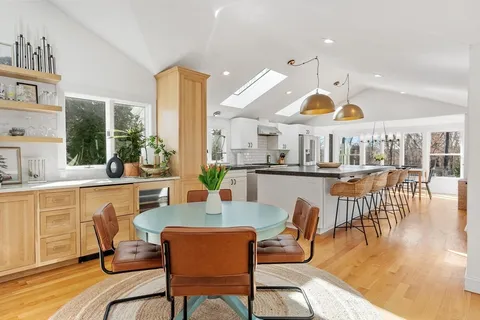 a dining room with wooden floor and large windows