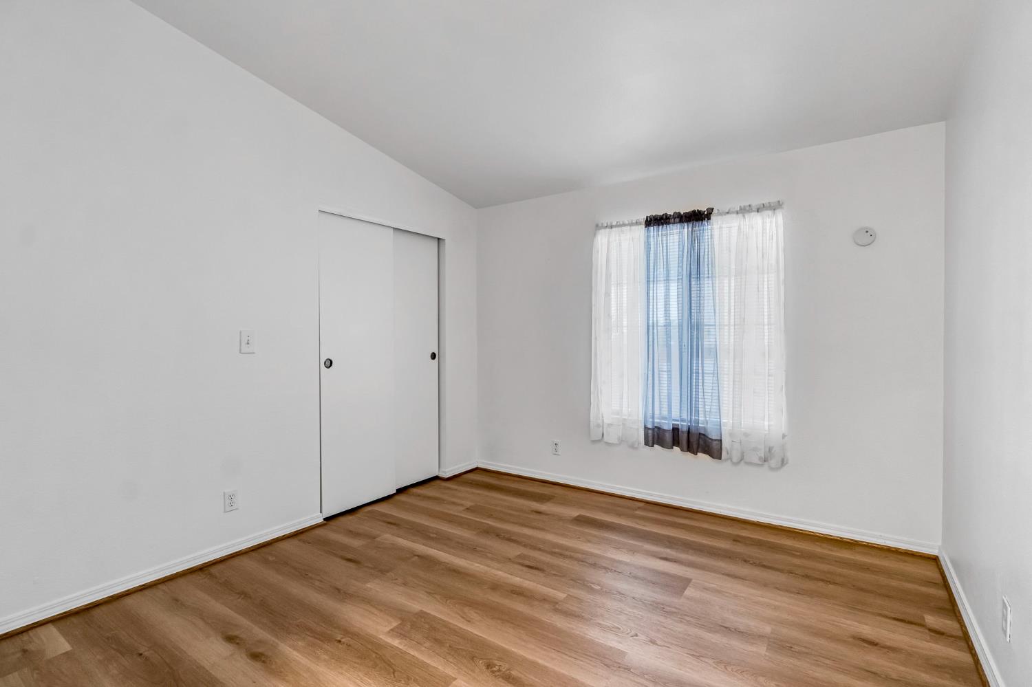 1218 East Cleveland Avenue, Unit 142 Madera, CA 93638 - Photo 18 of 32 a view of an empty room with wooden floor and a window