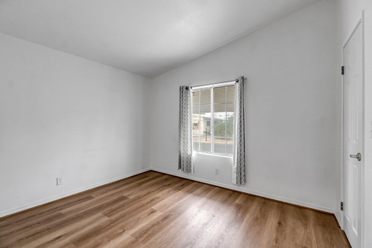 1218 East Cleveland Avenue, Unit 142 Madera, CA 93638 - Photo 19 of 32 an empty room with wooden floor and windows
