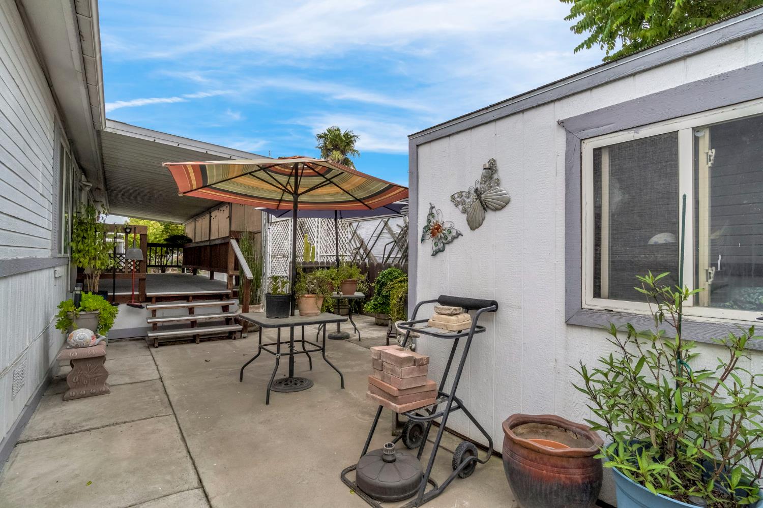 1218 East Cleveland Avenue, Unit 142 Madera, CA 93638 - Photo 31 of 32 a view of a patio with table and chairs potted plants with wooden fence