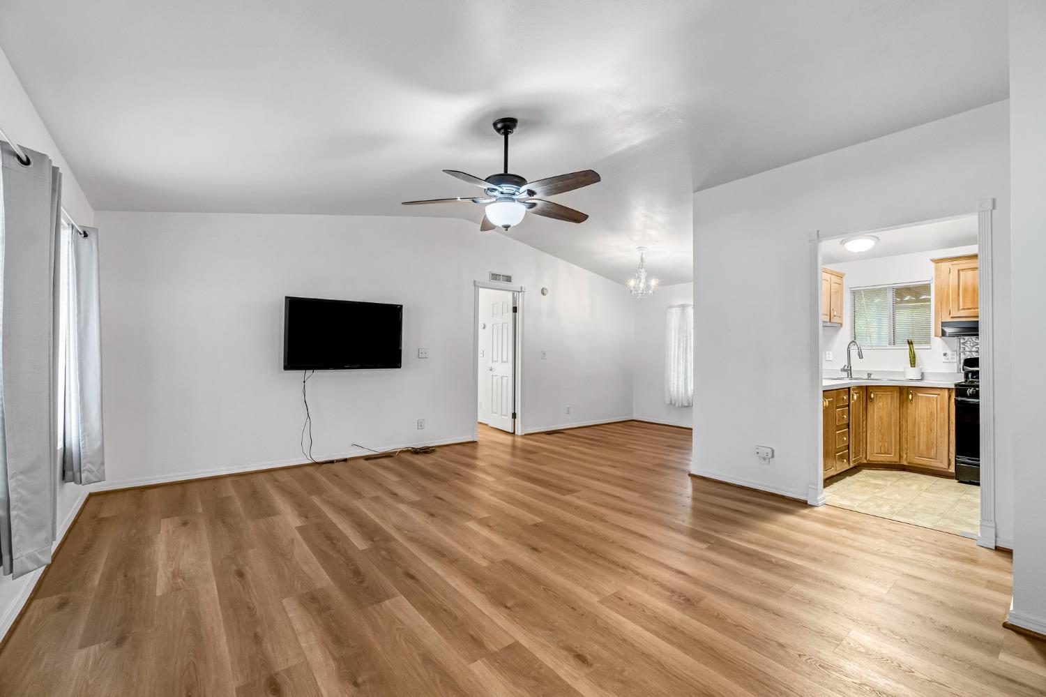 1218 East Cleveland Avenue, Unit 142 Madera, CA 93638 - Photo 5 of 32 a view of an empty room and kitchen with wooden floor
