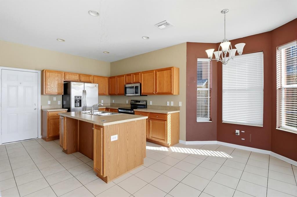 4059 Southwest 51st Road Ocala, FL 34474 - Photo 16 of 42 a kitchen with stainless steel appliances granite countertop a stove top oven a refrigerator a sink dishwasher with a dining table and chairs