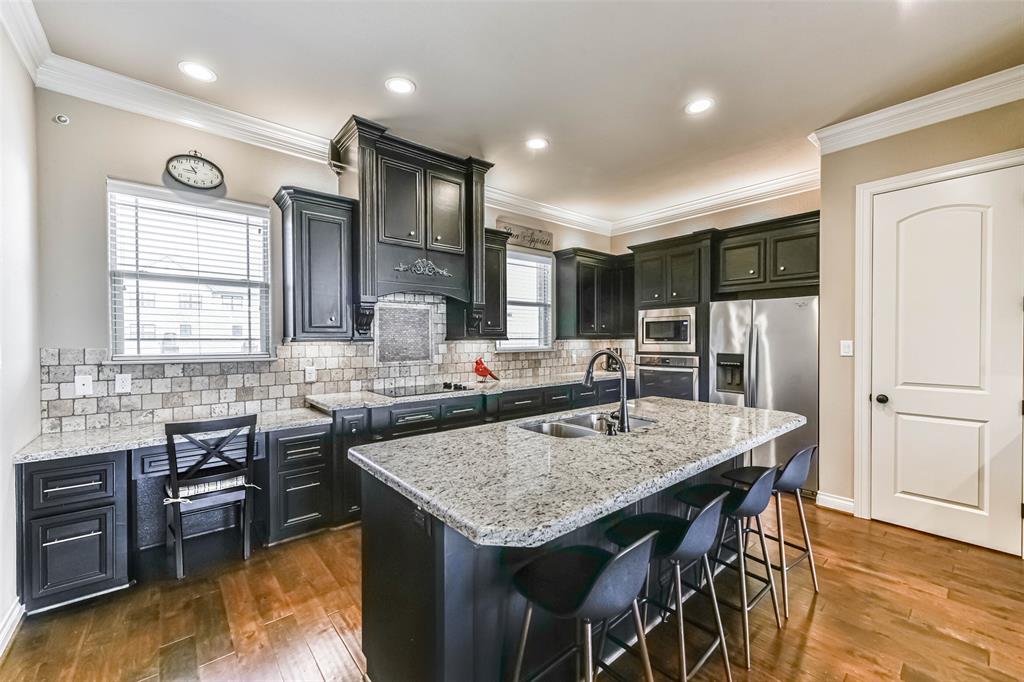 a kitchen with granite countertop a table chairs stove refrigerator and wooden floor