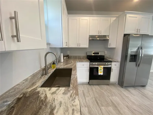 a kitchen with stainless steel appliances granite countertop a stove a sink and a refrigerator