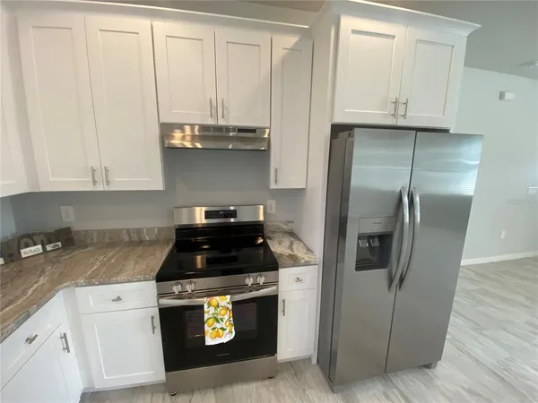 a kitchen with granite countertop white cabinets and stainless steel appliances