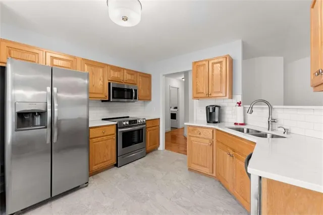 a large kitchen with stainless steel appliances granite countertop a sink a stove top oven a refrigerator with grey cabinets