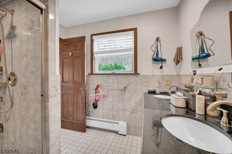 699 East Shore Road West Milford, NJ 07421 - Photo 29 of 50 a bathroom with a granite countertop sink a mirror and shower