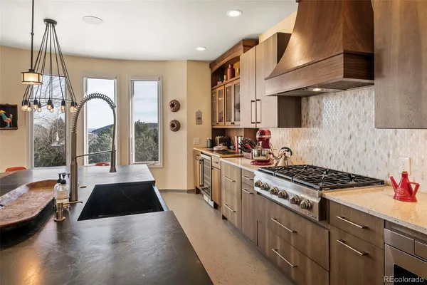 a kitchen with stainless steel appliances granite countertop a stove a sink dishwasher and white cabinets with wooden floor