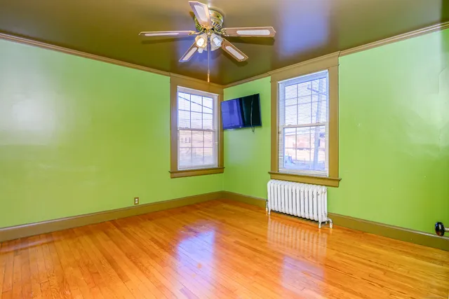 a view of an empty room with window and wooden floor