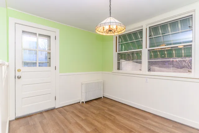 a view of an empty room with a window and chandelier