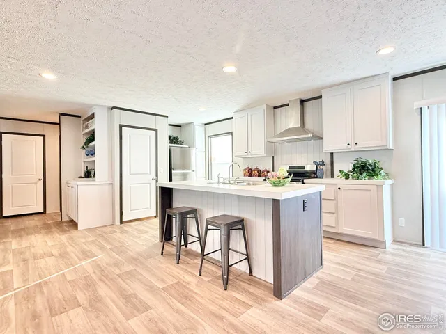 a kitchen with granite countertop a refrigerator a stove a sink and white cabinets with wooden floor