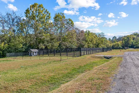 a view of a house with a big yard and large trees