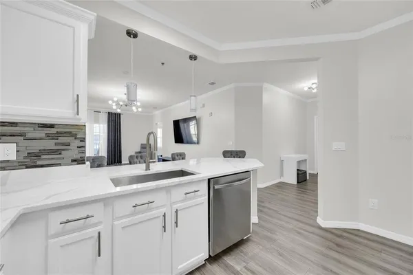 a view with cabinets a sink dishwasher a dining table and chairs
