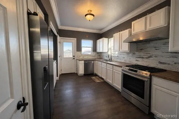 a kitchen with stainless steel appliances granite countertop a refrigerator a sink dishwasher a stove and a microwave oven with wooden floor