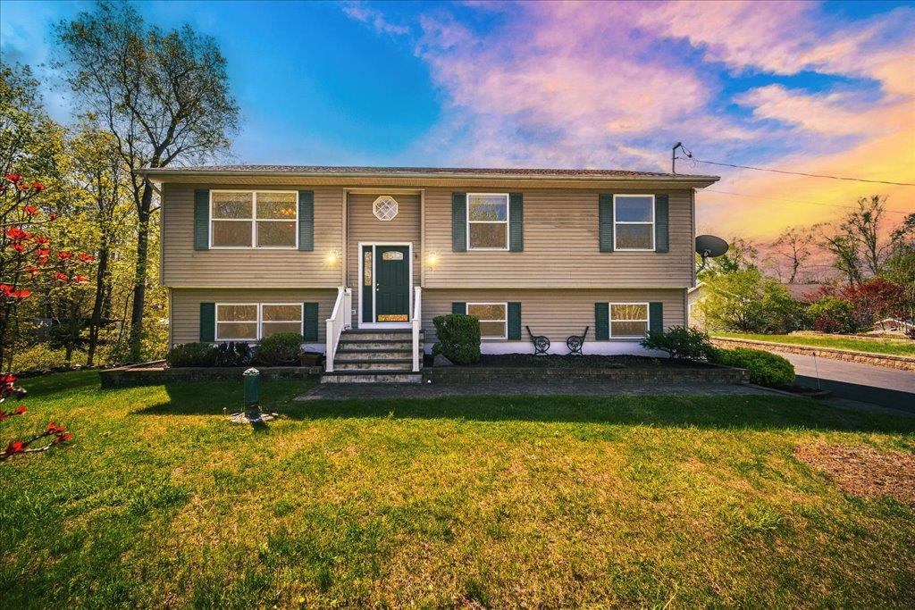 a view of a house with a yard and a large tree