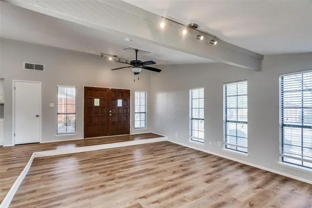 a view of an empty room with window and wooden floor