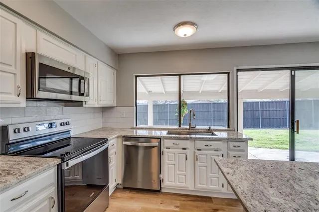 a kitchen with stainless steel appliances granite countertop a stove a sink and a microwave
